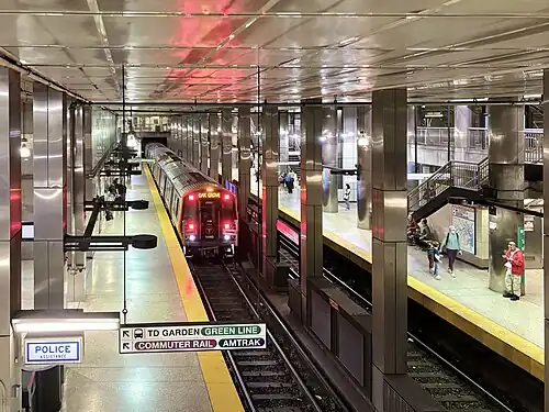 An overhead view of a metro train entering a subway station with square metal columns