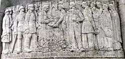 The relief on the Noyon monument aux mort which records the presentation to Noyon on 10 July 1920 of the Légion d'honneur and the Croix de guerre in recognition of the suffering and fortitude of the citizens of Noyon during the German occupation