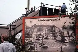 An observation deck in West Berlin with a view of Potsdamer Platz on the other side of the Berlin Wall, 1977. At the bottom of the steps a placard shows what the square looked like in 1929.
