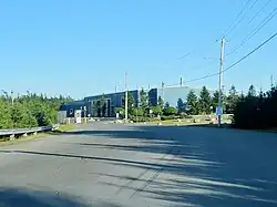 A large blue building off a main road with trees around it.
