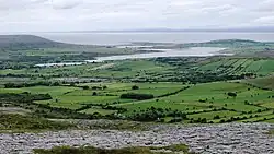 View northwest from Turlough Hill, with the Oughtmama churches at the foot of the hill, Corcomroe Abbey, two ruined castles and the Finavarra Martello Tower in the back