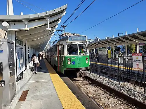 A light rail train at a surface station in the median of an urban street