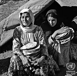 Two women holding flat bread