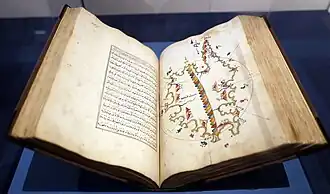 Large book open with Arabic text on one page and a multicolor illustrated map opposite