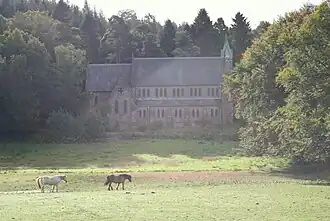 A photograph of St Margaret's Church, surrounded by trees, with a grass field in the foreground