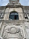 Entrance portal to the college, with reused 15th-century relief in foreground