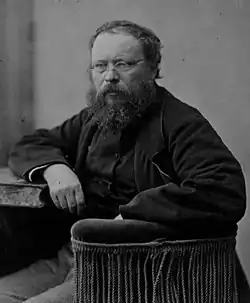Black-and-white photo of a bearded man with glasses wearing a dark coat