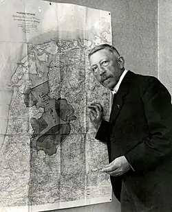 Portrait of a white man in a suit showing a map
