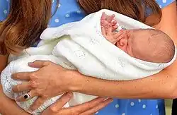 A newborn Prince George wrapped in white cloth and in the arms of his mother