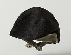 A rounded, furry cap with a velvet bow for securing underneath the wearer's chin.