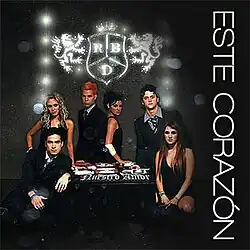 Black background with the band's logo in silver, with the song's title in white upper-case lettering on the right side, going from top to bottom. The group sit surround a table: Alfonso and Anahí appear on the left side, with the former sitting down while the latter stands behind him; to Anahí's left, Christian and Maite stand back-to-back, with Christopher standing behind Dulce on the right side, who sits in a chair in front of him.