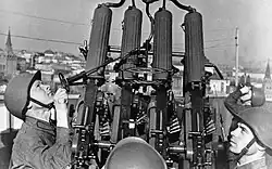 A helmeted soldier adjusts an four barreled anti aircraft gun