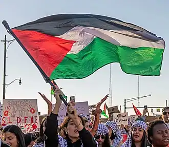 A woman waving a Palestinian flag at a protest.