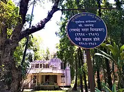 blue plaque in the foreground and a bungalow in background