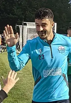 Player smiling and raising his left hand to high five a fan