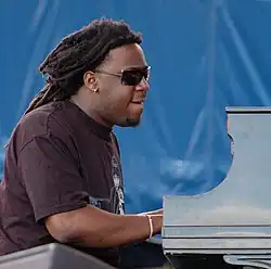 Side view of a man with long hair and sunglasses playing the piano