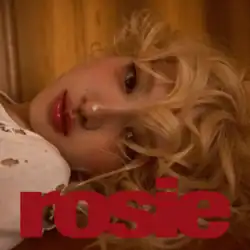 Close-up of Rosé lying down with blonde curly hair, gazing at the camera. The word 'rosie' is written in bold red text across the bottom of the image.