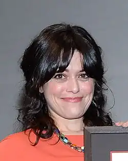 head and shoulder photo of smiling white woman with black shoulder-length hair, holding an award