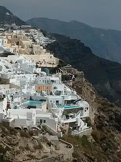Enclave of structures built into the side of a steep cliff. Swimming pools are visible.