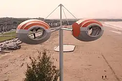 An artwork consisting of dual wind turbines overlooking a seafront.