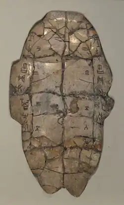 Tortoise plastron with divination inscription from the Shang dynasty, dating from the reign of King Wu Ding. The piece has complementary charges down the left and right sides. Cracks caused by applying a heat source to the reverse are numbered 1–6 on the left and 1–7 on the right. The outcome of the interpretation of these cracks is recorded at bottom right.