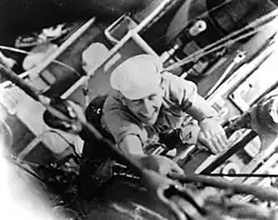 Black and white photograph of Munro climbing a ship's rigging