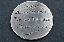 Image of silver disc with engraved text stating "King Street, Bristol Theatre, May 30 1766" on a plain background.
