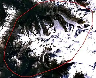 Satellite imagery of mountainous terrain with an oval-shaped outline depicting the approximate boundaries of a geological feature