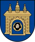 A coat of arms depicting a grey castle with three towers topped by crosses with a human head on the front door all on a blue background