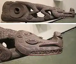 A wooden handle disconnected from a drum, carved as a crocodile