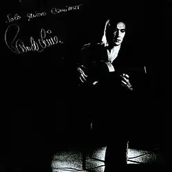 A high contrast, black and white depiction of a man sitting in a chair playing a flamenco guitar.