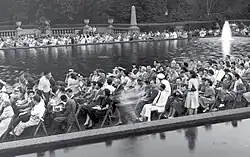 People sitting in chairs lining a fountain