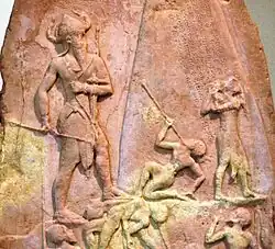 Victory Stele of Naram-Sin, c. 2230 BC. It shows him defeating the Lullibi, a tribe in the Zagros Mountains, and their king Satuni, trampling them and spearing them. Satuni, standing right, is imploring Naram-Sin to save him.[61] Naram-Sin is also twice the size of his soldiers.