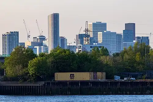 The emerging cluster in Stratford in April 2023 as viewed from Greenwich Peninsula. Stratford has been undergoing regeneration, associated with the 2012 Summer Olympics, which largely took place in Queen Elizabeth Olympic Park to the west of the cluster. Seen on the left is 150 High Street at a height of 135m. The tallest building in the cluster, Manhattan Loft Gardens at 143m, is seen at the back.