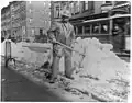 Street types of New York City-Street cleaner with pick ax standing in front of pile of snow