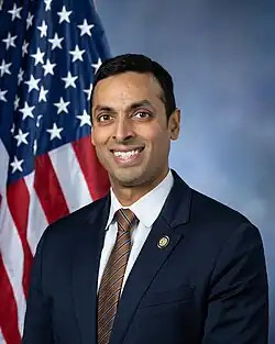 Official House portrait of Subramanyam smiling in front of the U.S. flag, wearing a black suit with Seal of Virginia lapel pin, light purple shirt, and striped red, black, and white tie.