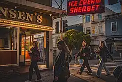A group of young women stroll by Swensen's at sunset.