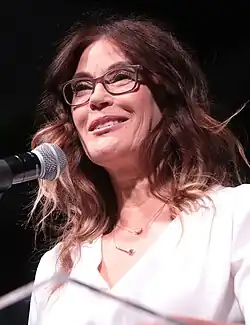 middle-aged woman of European descent, slim upper body, long brown hair, wearing red dress.