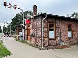 A brick-style ground-level building with the red logo of IG Metall trade union attached to the side. Visible in the background are traffic lights and train tracks.