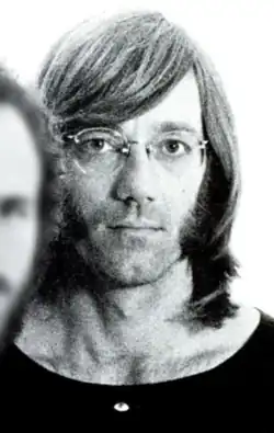 Close up photo of Ray Manzarek looking into the camera, wearing glasses and hair parted to the side.