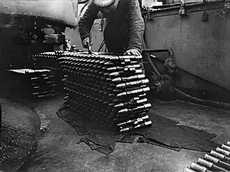 A stack of 14 linked rounds of naval pom-pom ammunition.