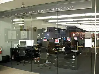 Interior view of a screening room with multiple rows of seats facing a large projection screen, dedicated to theater patron Lucille Lortel