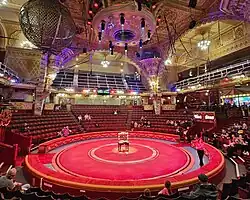 a circus arena seen from one half of the seating, looking towards the ring and the other side of the seating area