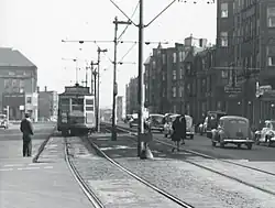 A streetcar next to a small platform in the median of an urban street