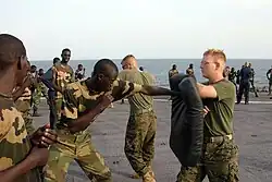US Navy 051103-M-2175L-200 U.S. Marine Corps Lance Cpl. Ryan Papa, right, assigned to 2nd Platoon, Company C, 1st Battalion, 8th Marine Regiment, holds a striking pad for a member of the Senegalese 90th Naval Infantry.