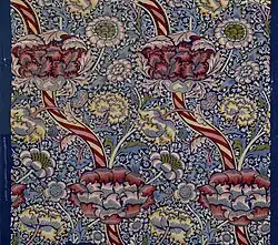Section of "Wandle" fabric, a complex floral design in white, yellow, and shades of red and pink on a blue and white background.