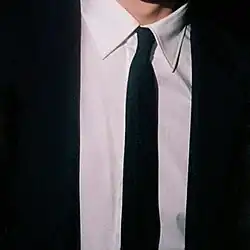 A cropped photo of a man in a black suit and tie