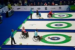Wheelchair curling uses a specially adapted long stick to launch the "rock" down the ice. These players are delivering rocks in the 2010 Vancouver Paralympics.