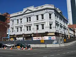 A white, three storey building surrounded by construction hoardings