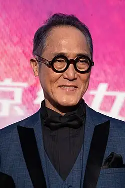 head and shoulders image of Sano Shiro wearing dark suit and bow tie and facing to right of audience